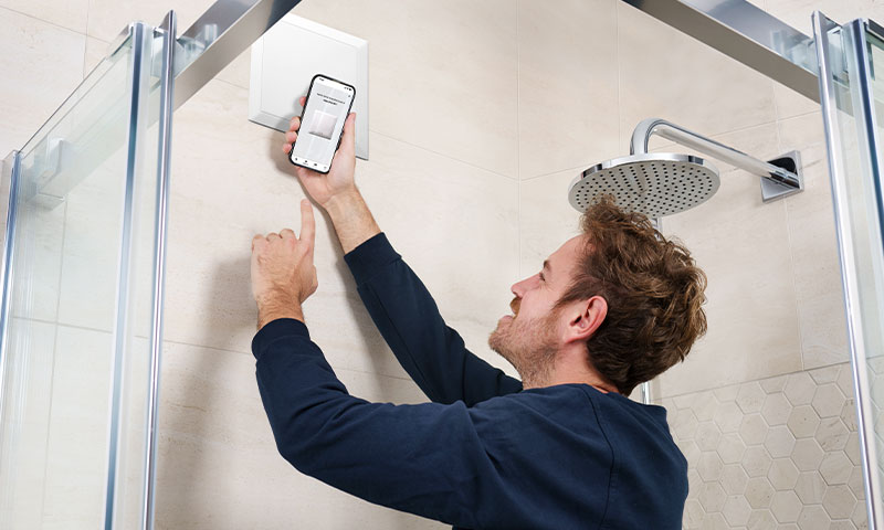 Installateur im Badezimmer nutzt die neue App für den Helios ELS NFC